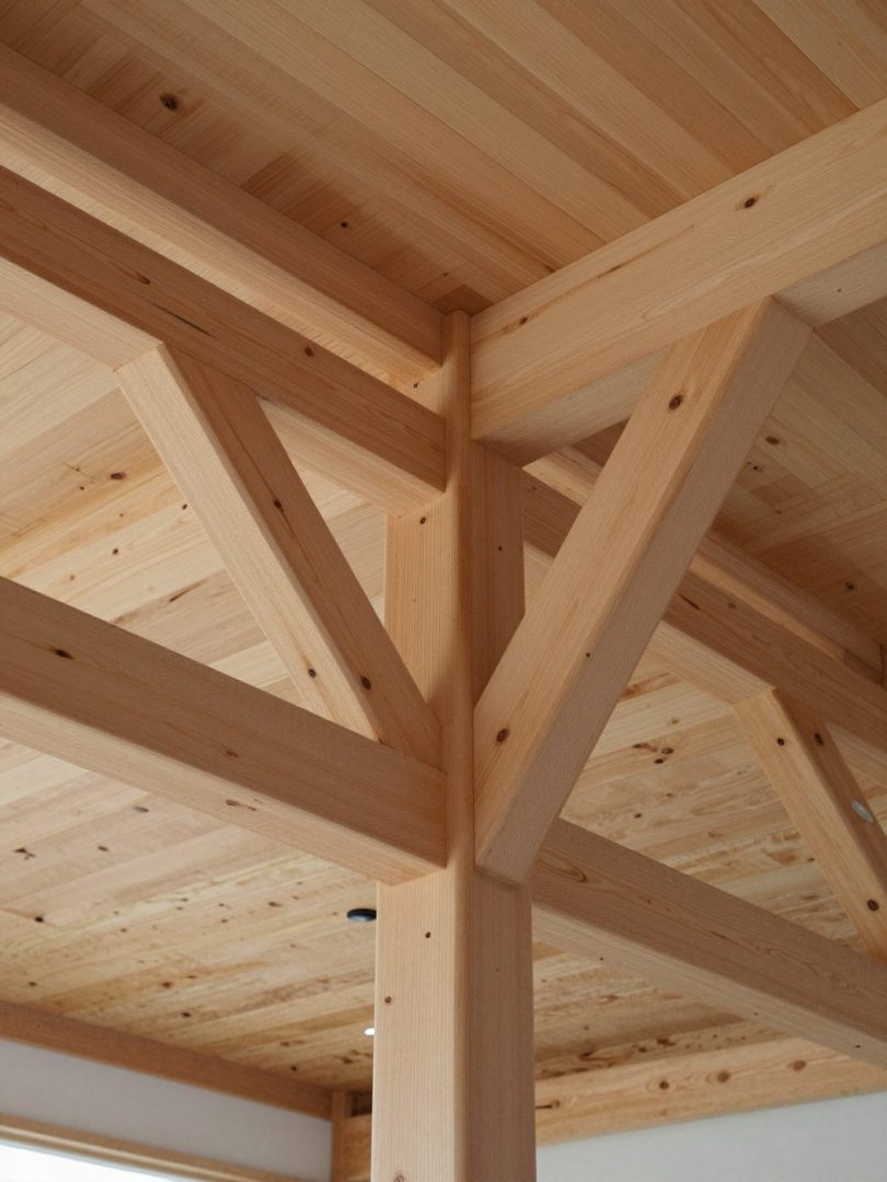 Looking up at glulam beams branching from a column into a ribbed wooden ceiling.