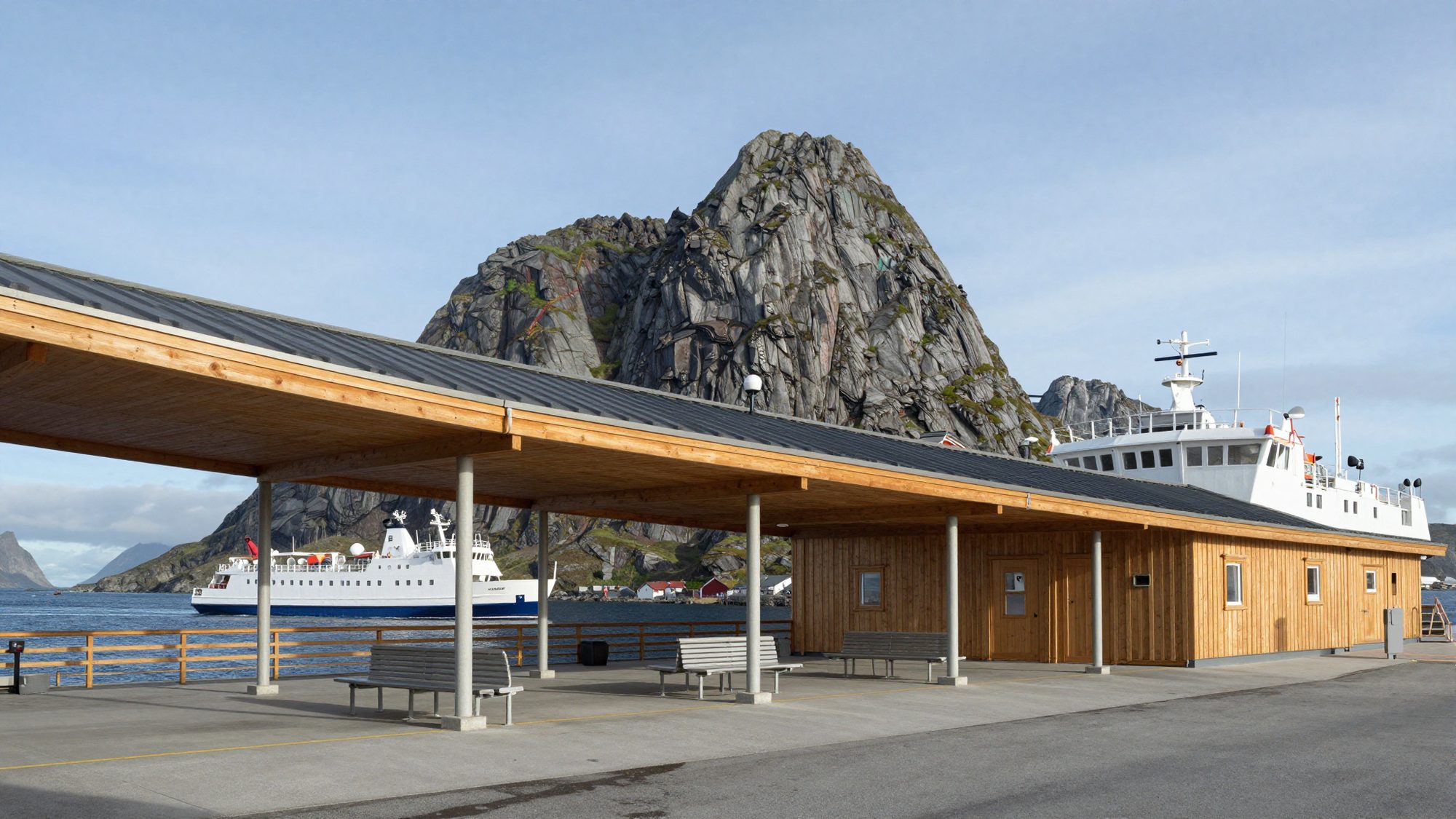 A long cantilevered timber roof over a ferry terminal, a white ferry and jagged mountains behind.